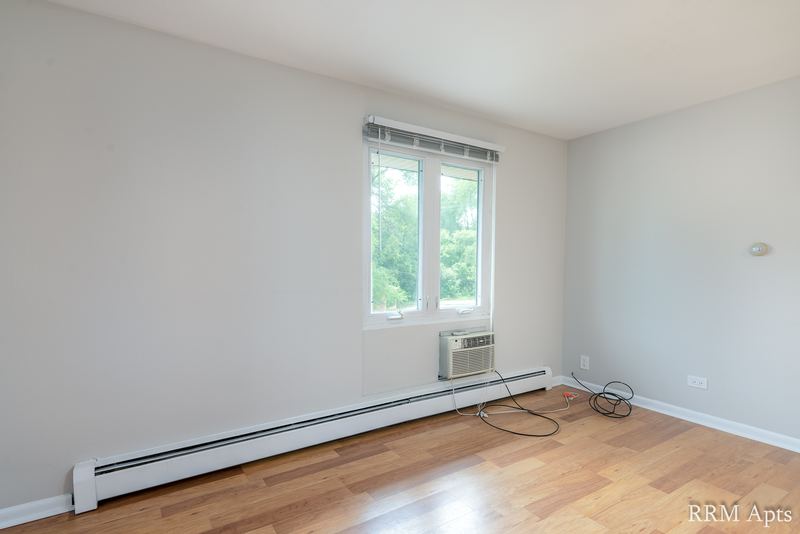 Bedroom with wood floor, one window with a wall air conditioner below it and baseboard radiator, East Park apartment 2
