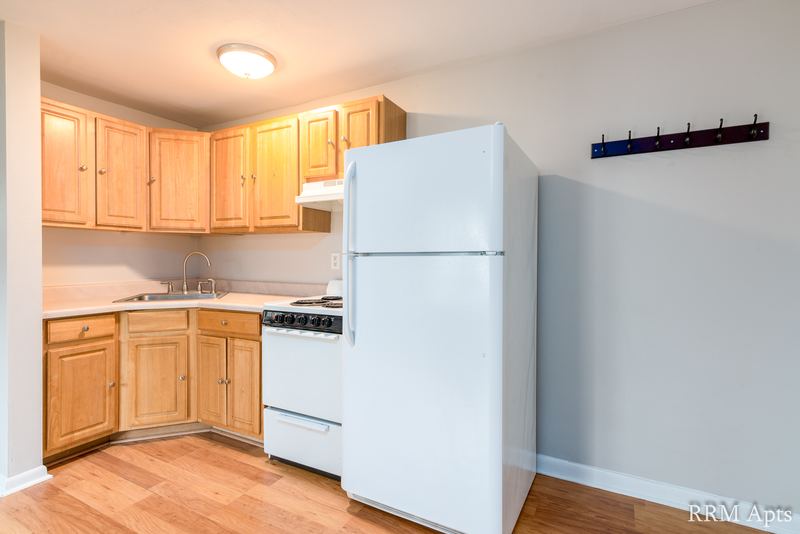 Kitchen with light oak cabinets, white refrigerator, white stove and white counter, East Park apartment 2
