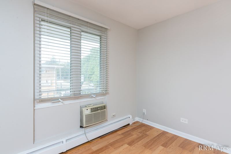 Bedroom with wood floor, one window with blinds, a wall air conditioner and baseboard radiator, East Park apartment 3