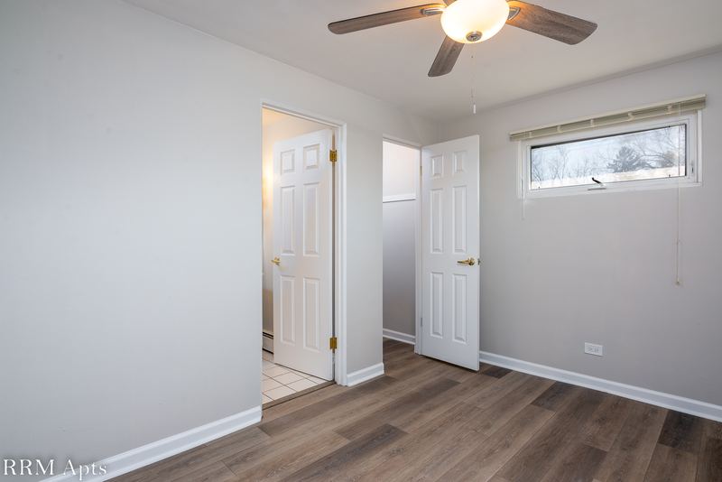 Bedroom with wood floor, ceiling fan, one window, white doors and a doorway to the bathroom, East Park apartment 4