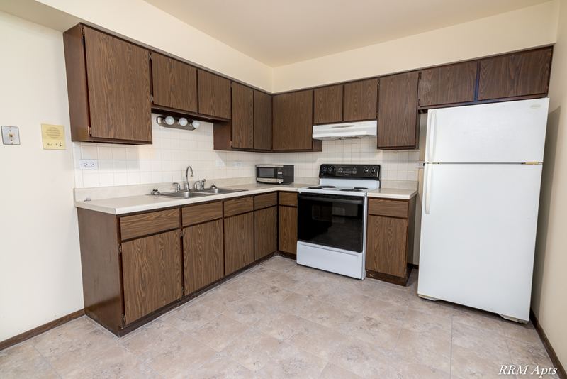 Kitchen with dark wood cabinets, white refrigerator, white stove and beige tile floor, John Mogg apartment 32927 102 S