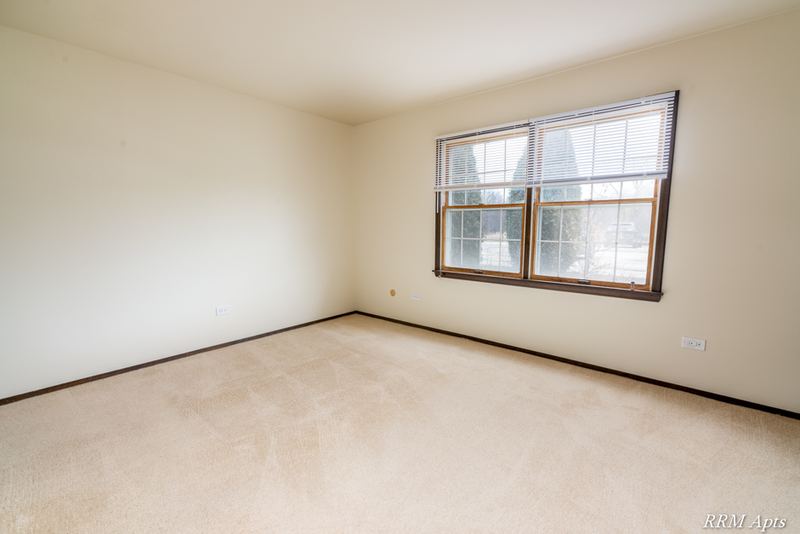 Carpeted bedroom with one wood-trimmed window and cream walls, John Mogg apartment 32927 102 S
