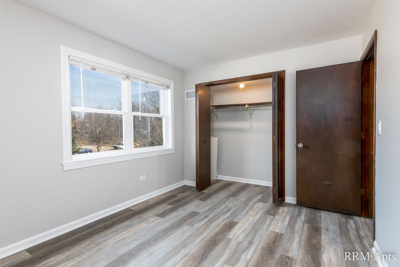 Bedroom with gray wood-look floor, a window, open closet and a wood door, John Mogg apartment 32927 202
