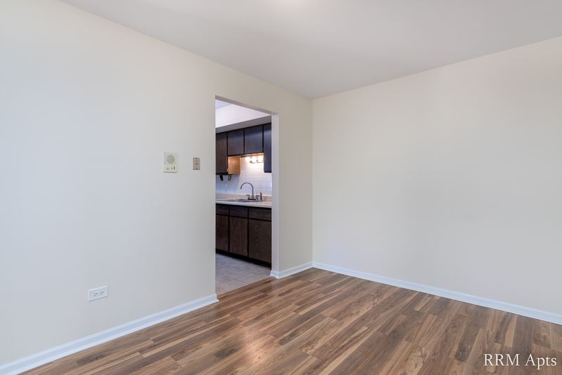 Empty room with wood floor, cream walls and a doorway to the kitchen, John Mogg apartment 32927 203