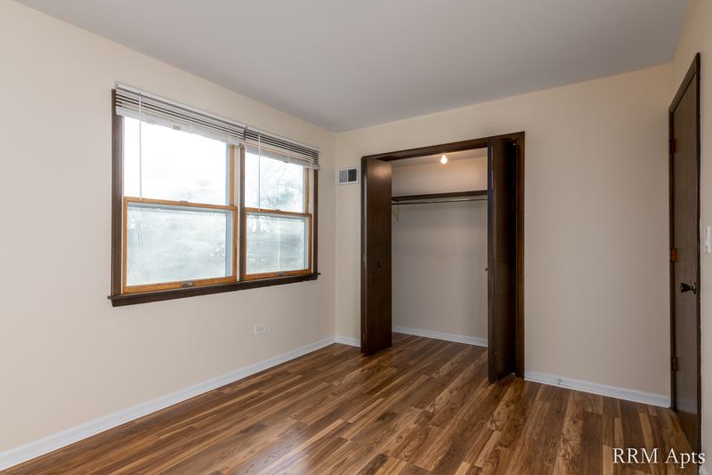 Bedroom with wood floor, a wood-trimmed window, open closet and a wood door, John Mogg apartment 32927 203