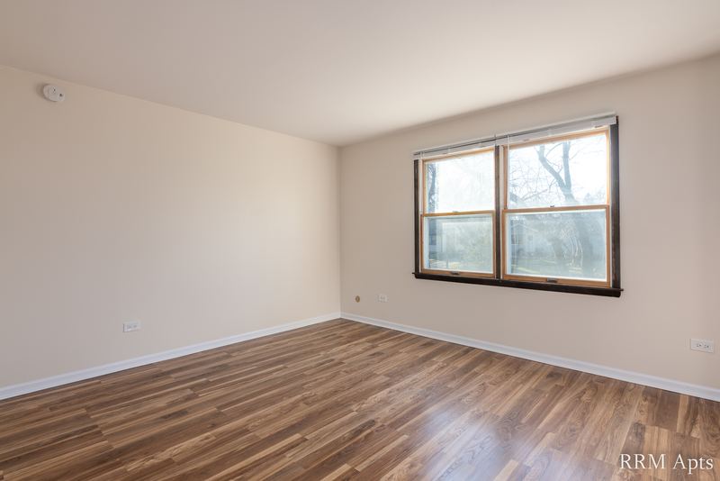Bedroom with wood floor and a wood-trimmed window looking out at trees, John Mogg apartment 32927 203