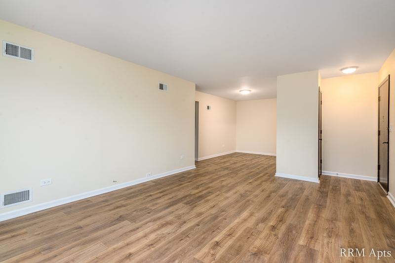 Living room with wood floor, wood entry door and a hallway with closet, John Mogg apartment 32927 301