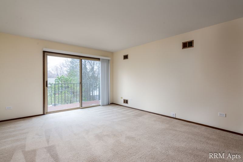 Carpeted living room with cream walls and a sliding glass door to a balcony, John Mogg apartment 32927 304