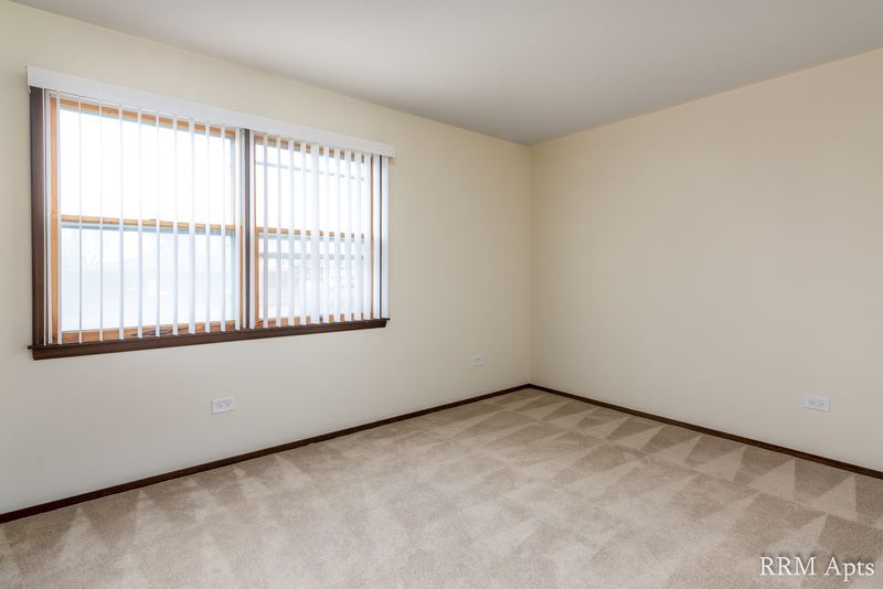 Carpeted bedroom with cream walls and a wood-trimmed window with vertical blinds, John Mogg apartment 32927 304