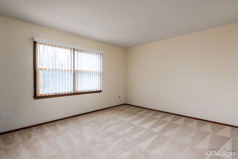 Carpeted bedroom with one wood-trimmed window looking out at trees, John Mogg apartment 32927 304