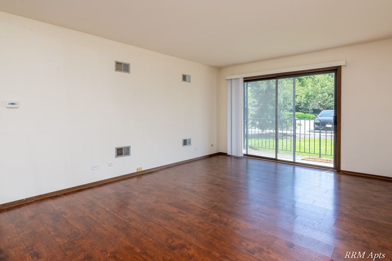 Living room with wood floor and a sliding glass door to a patio with iron railing, John Mogg apartment 32985 102