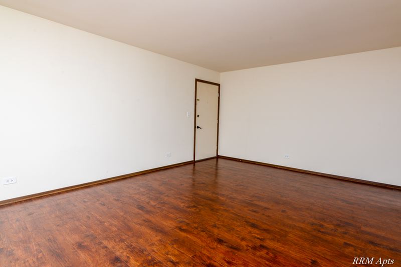 Living room with wood floor, cream walls and a wood entry door, John Mogg apartment 32985 102