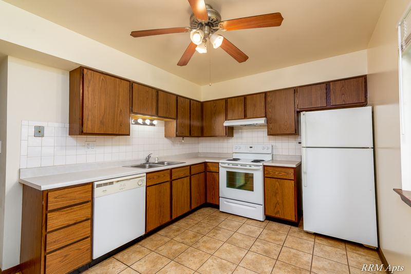Kitchen with dark wood cabinets, white stove, white refrigerator, ceiling fan and tile floor, John Mogg apartment 32985 102