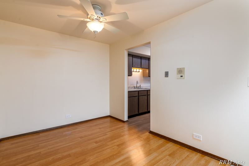Dining area with wood floor, ceiling fan and a doorway to the kitchen with oak cabinets, John Mogg apartment 32985 201