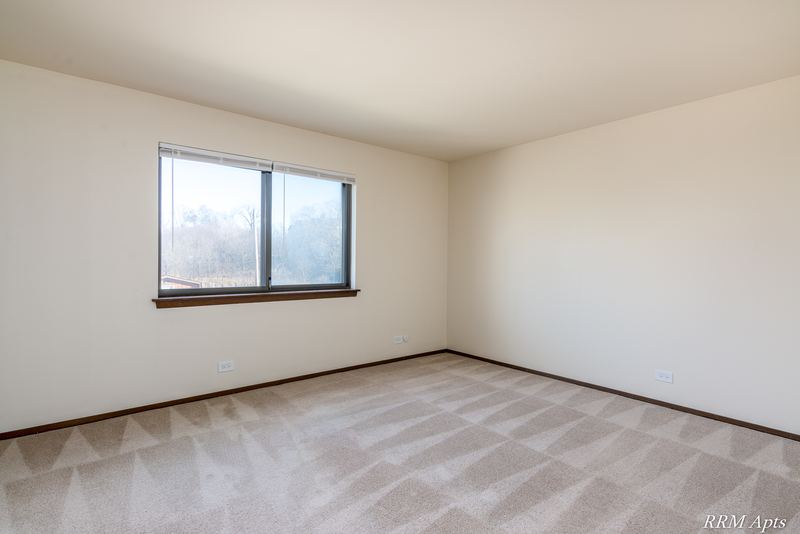 Carpeted bedroom with cream walls and one wood-trimmed window, John Mogg apartment 32985 201