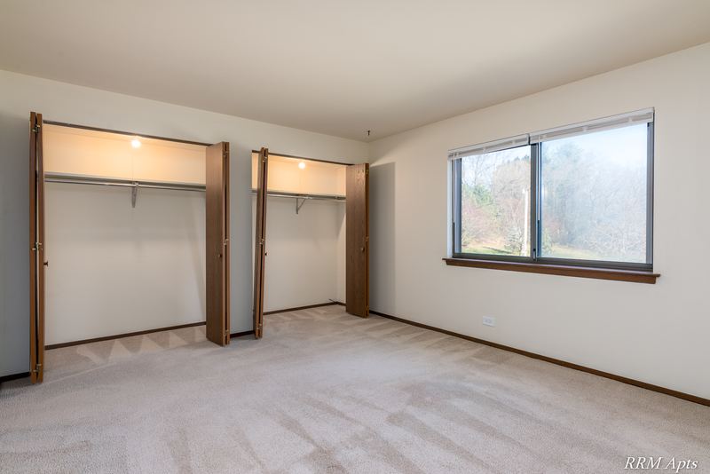 Carpeted bedroom with two open closets and a wood-trimmed window, John Mogg apartment 32985 201