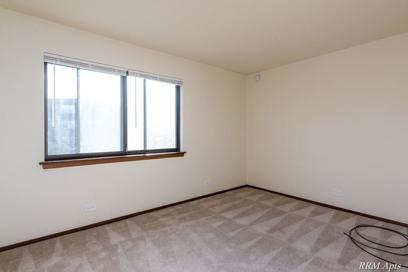 Carpeted bedroom with a wide three-pane window and cream walls, John Mogg apartment 32985 201