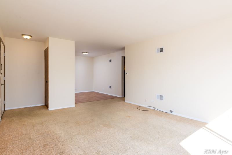 Living room with beige carpet, open partition wall and doorway to the kitchen, John Mogg apartment 32985 302