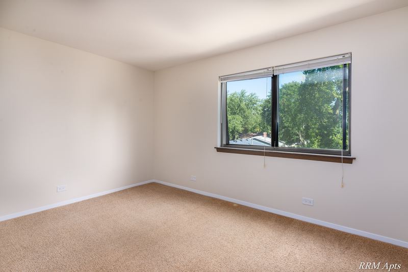 Bedroom with beige carpet and a window looking out on trees, John Mogg apartment 32985 302