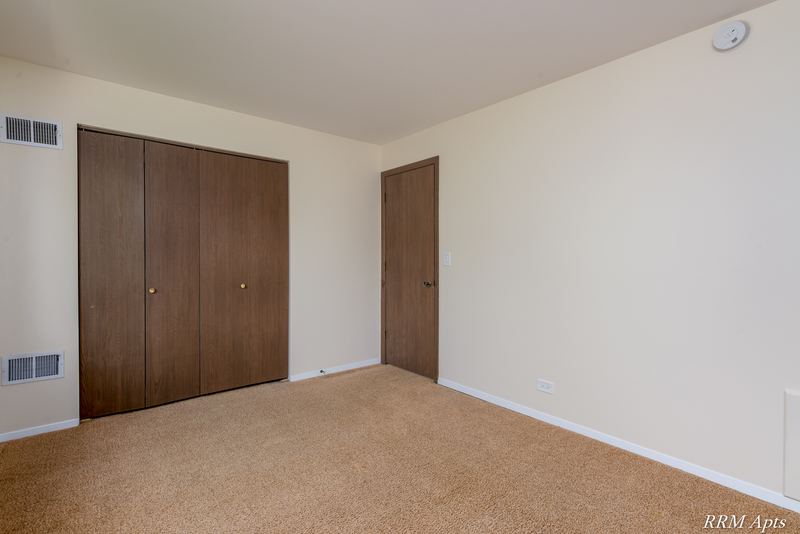 Bedroom with beige carpet, wood double-door closet and entry door, John Mogg apartment 32985 302