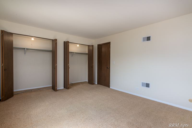 Bedroom with beige carpet, open closet with shelf and rod, and a wood door, John Mogg apartment 32985 302