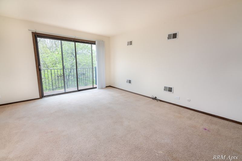 Living room with beige carpet and a sliding glass door to the balcony, John Mogg apartment 32985 304 N