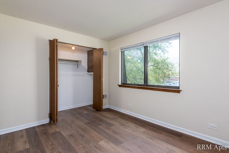 Bedroom with wood laminate floor, open closet with shelf and a window, John Mogg apartment 32985 304