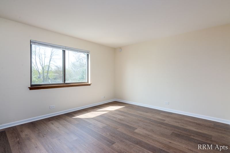 Bedroom with wood laminate floor and a single window with trees outside, John Mogg apartment 32985 304