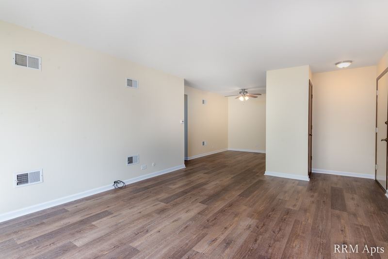 Living room with wood laminate floor, partition wall and a ceiling fan in the room beyond, John Mogg apartment 32985 304