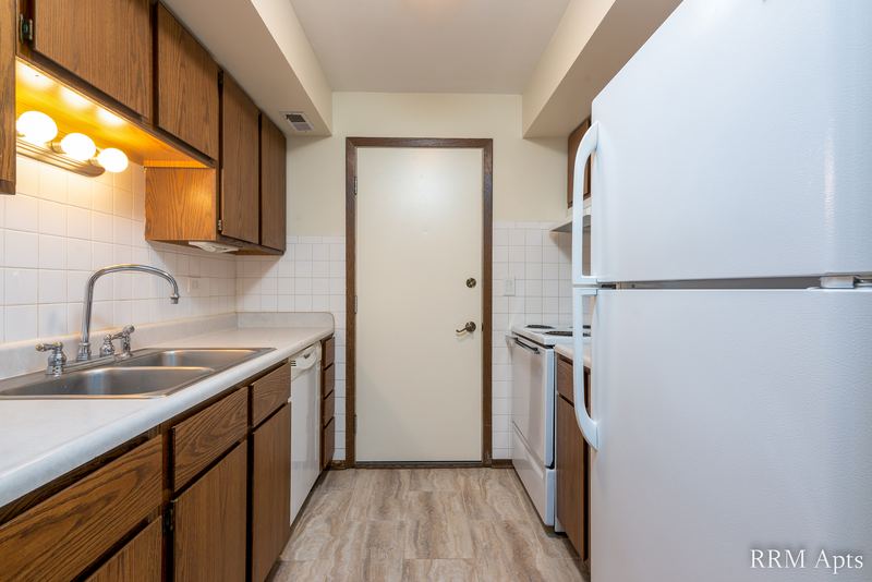 Kitchen with wood cabinets, white refrigerator, stove and dishwasher, and tile backsplash, John Mogg apartment 32985 304