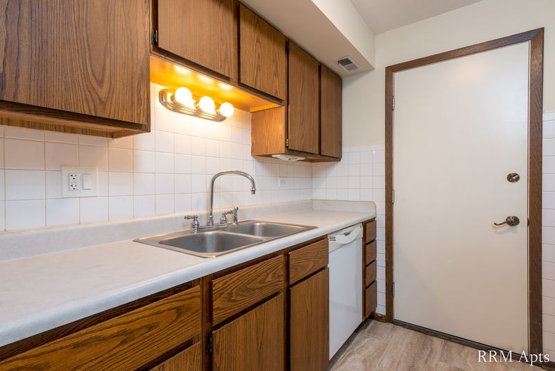 Kitchen with wood cabinets, stainless sink, white dishwasher and under-cabinet light, John Mogg apartment 32985 304