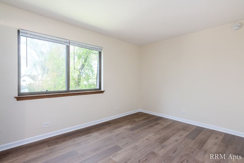 Bedroom with wood laminate floor and a window looking out on trees, John Mogg apartment 32985 304
