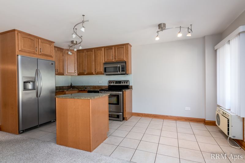 Kitchen with wood cabinets, stainless refrigerator and stove, island and tile floor, Maple Avenue apartment 101