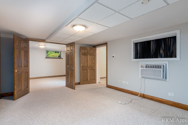 Bedroom with beige carpet, drop ceiling, wood doors and a window with wall air conditioner, Maple Avenue apartment 101