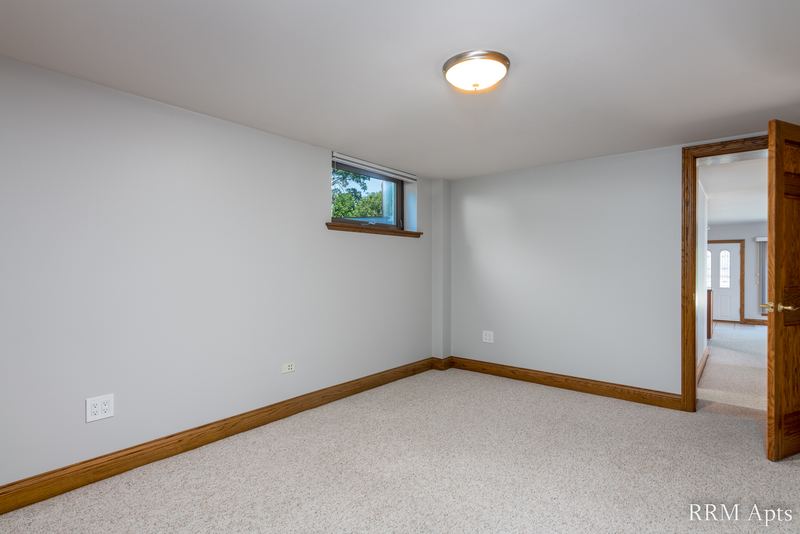 Bedroom with beige carpet, a small high window, wood door and flush ceiling light, Maple Avenue apartment 101