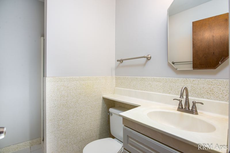 Bathroom with beige tile wainscot, white vanity, wood medicine cabinet and toilet, Maple Avenue apartment 1B