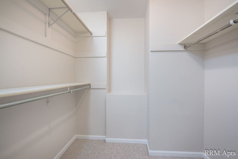 Walk-in closet with beige carpet and wire shelves and rods on two walls, Maple Avenue apartment 1B