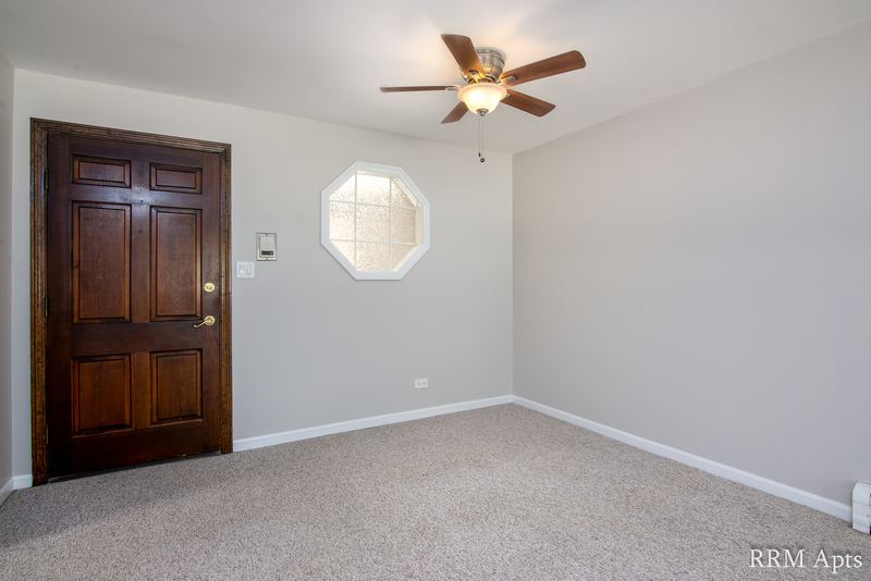 Entry with dark wood door, octagon window, ceiling fan and beige carpet, Maple Avenue apartment 1B