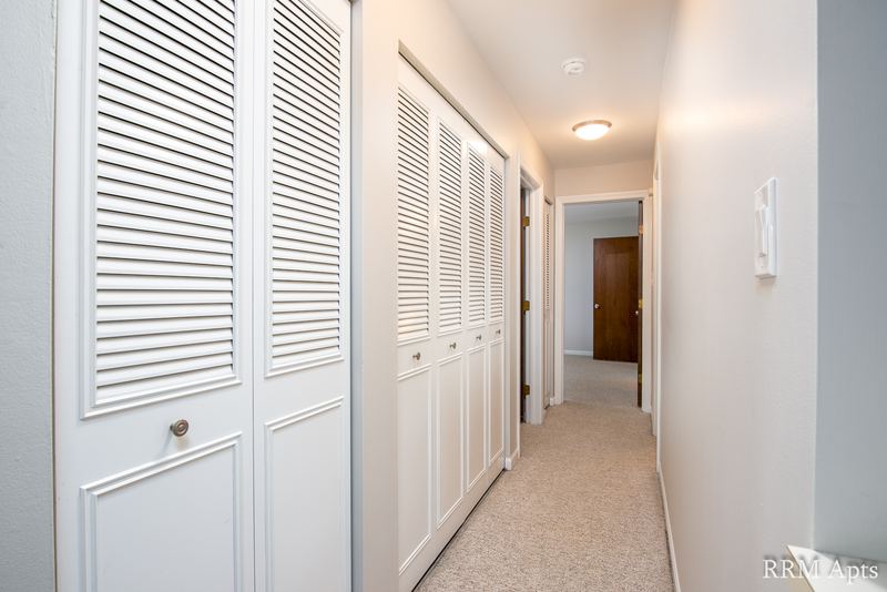 Hallway with white louvered closet doors, beige carpet and doorways to the bedrooms, Maple Avenue apartment 1B