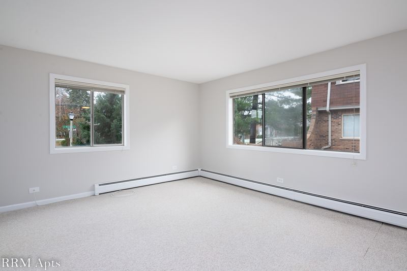 Living room with beige carpet, gray walls, two windows and baseboard heat, Maple Avenue apartment 1E