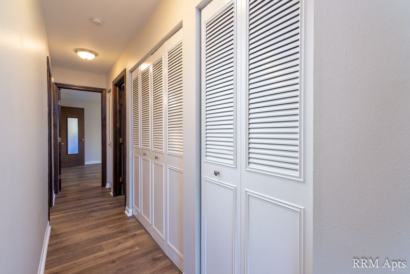 Hallway with white louvered closet doors, wood laminate floor and doorways to the bedrooms, Maple Avenue apartment 1F