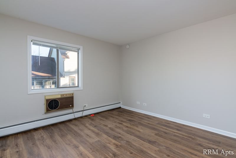 Bedroom with wood laminate floor, a window with wall air conditioner and baseboard heat, Maple Avenue apartment 1F