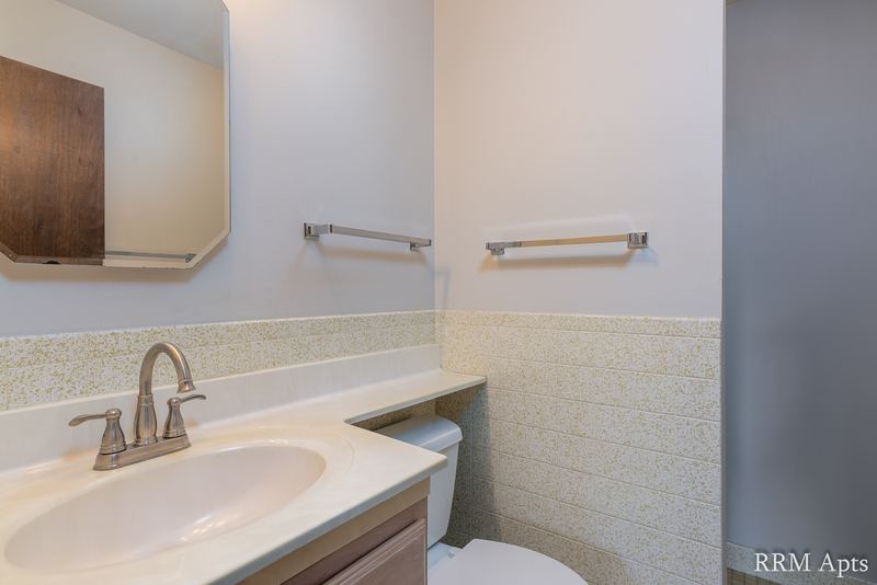 Bathroom with white vanity, wood medicine cabinet, beige tile wainscot and towel bars, Maple Avenue apartment 1F