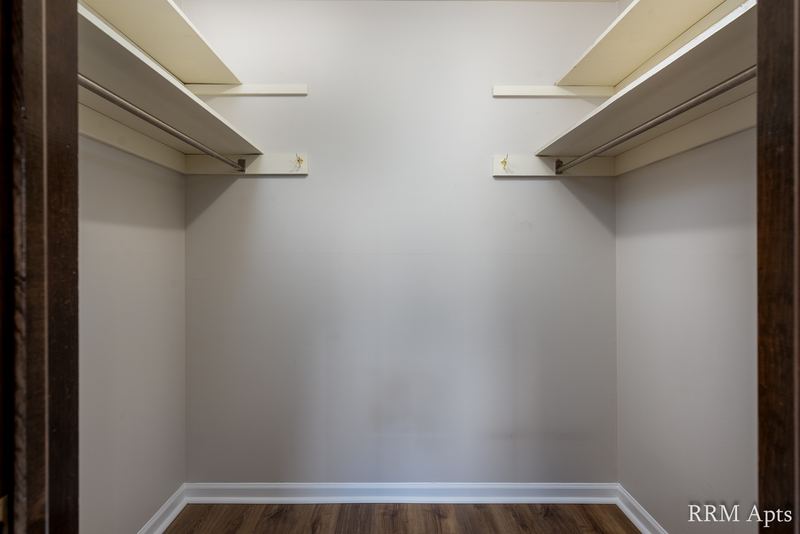 Walk-in closet with wood laminate floor and wire shelves and rods on both sides, Maple Avenue apartment 1F