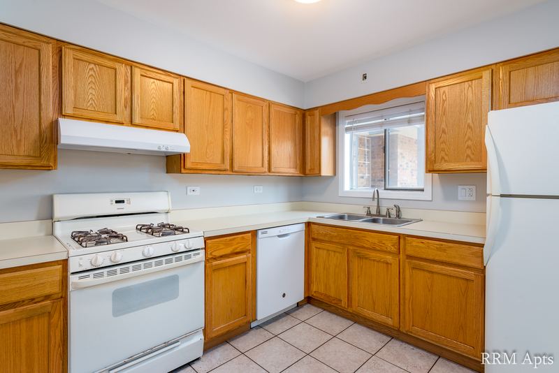 Kitchen with wood cabinets, white gas stove, dishwasher and refrigerator, and a window, Maple Avenue apartment 1H