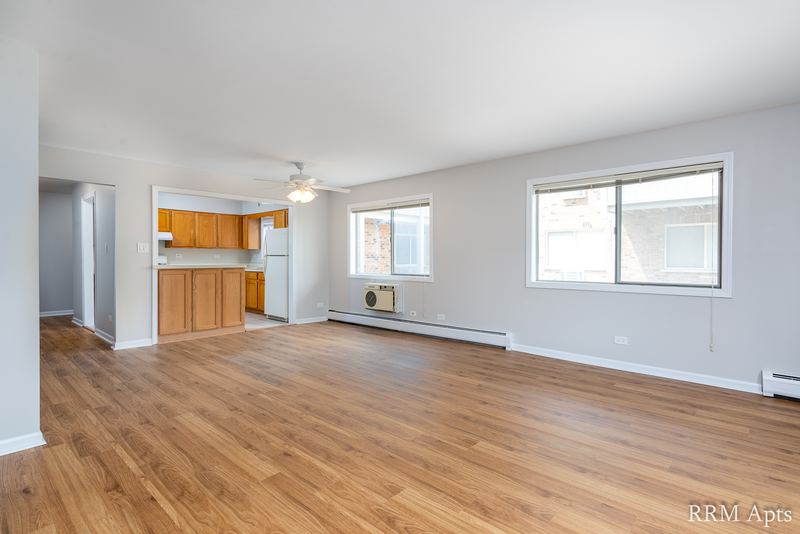 Living room with wood laminate floor, ceiling fan, wall air conditioner and open kitchen beyond, Maple Avenue apartment 1H