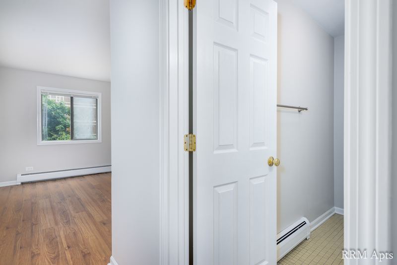 Bedroom with wood laminate floor, a window, white doors and baseboard heat, Maple Avenue apartment 1H