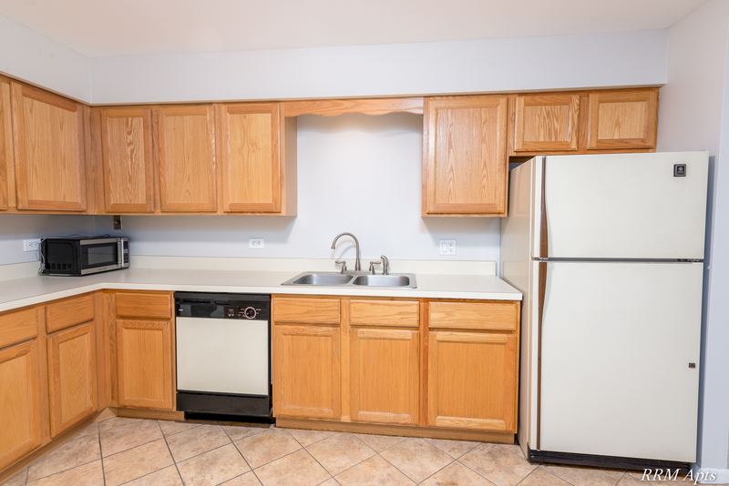 Kitchen with wood cabinets, stainless sink, white dishwasher, refrigerator and microwave, Maple Avenue apartment 1J