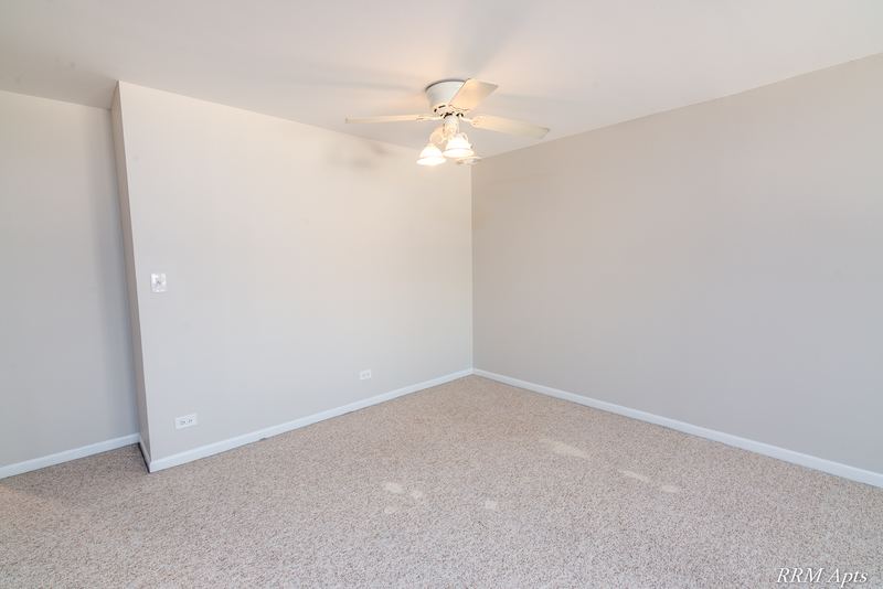 Dining area with beige carpet, flush ceiling light and an angled partition wall, Maple Avenue apartment 1J
