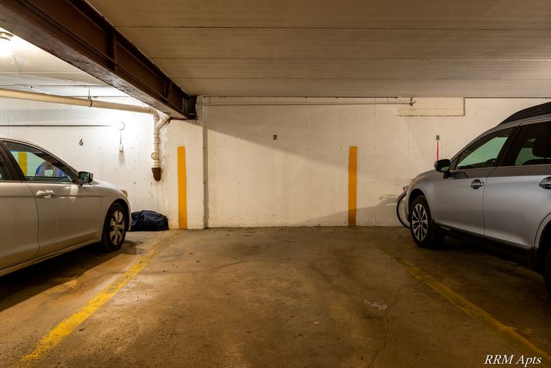 Indoor parking garage with concrete floor, yellow-striped stalls and parked cars, Maple Avenue apartment 2C
